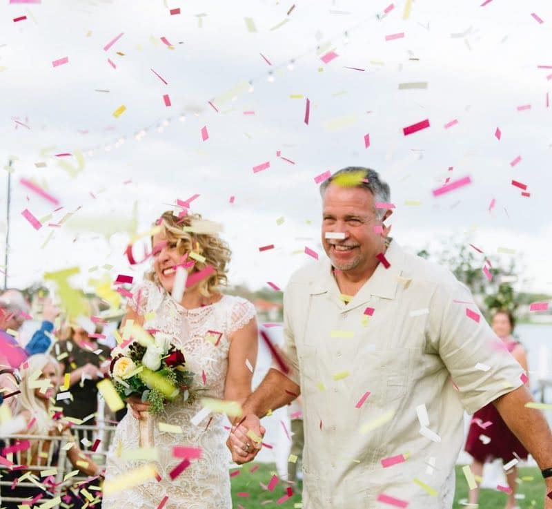bride and groom smiling walking back down the aisle after their wedding, with confetti flying around them