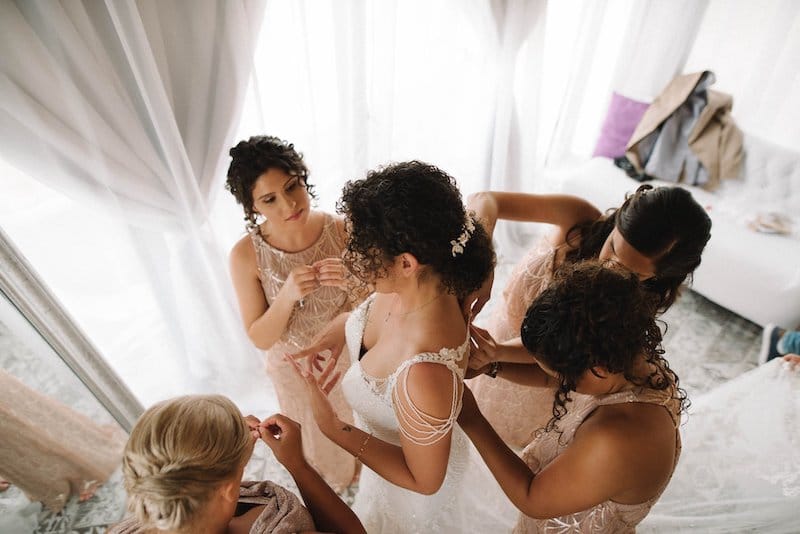 bridesmaids helping put the finishing touches on the bride before her wedding