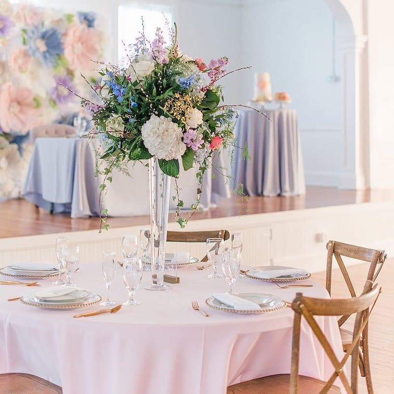round table with a tall flower centerpiece and a large flower wall behind the sweetheart table