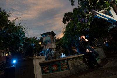 man and woman sitting on edge of fountain at sunset