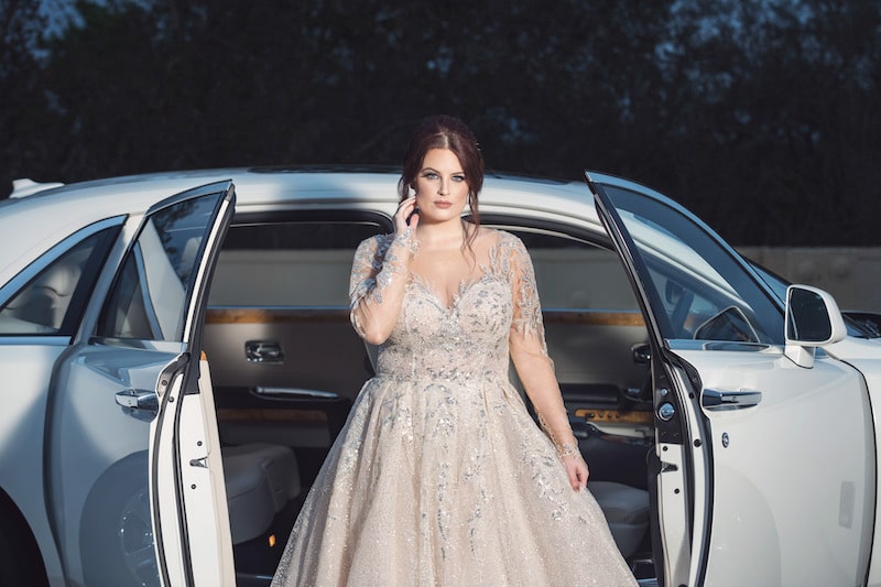 bride standing next to white car with side doors open