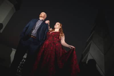 woman in red dress resting her arm on man in blue suit