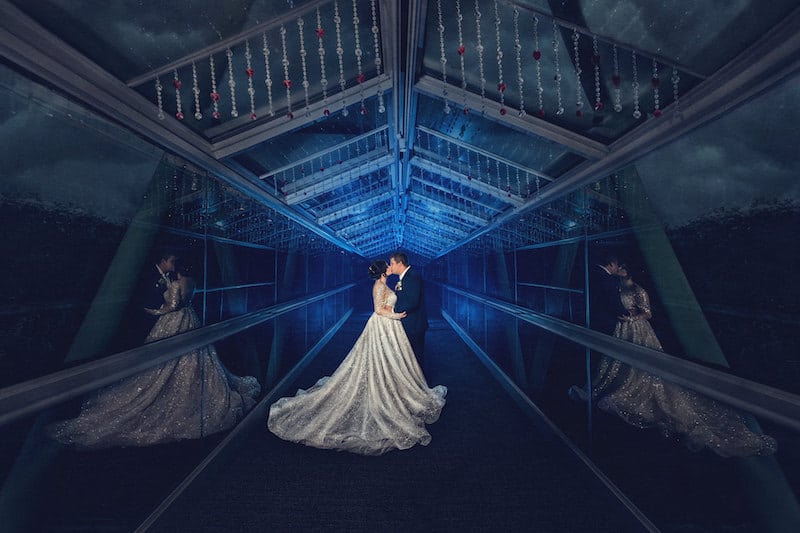 bride and groom kissing on covered walking bride showered in blue light