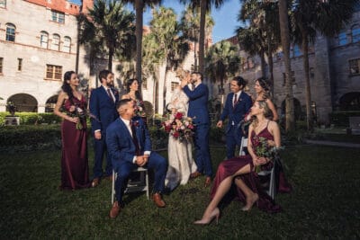 bride and groom kissing in courtyard area while bridal party looks on