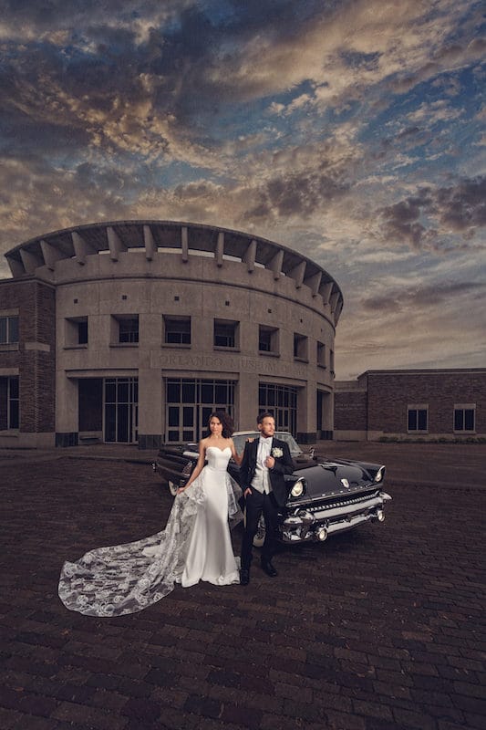 bride and groom standing in front of classic black convertible