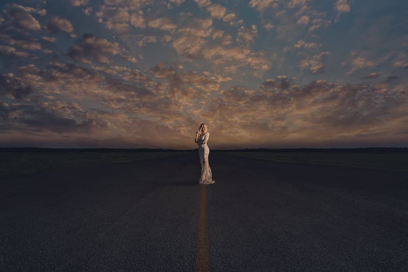 bride standing in the middle of a large roadway at sunset