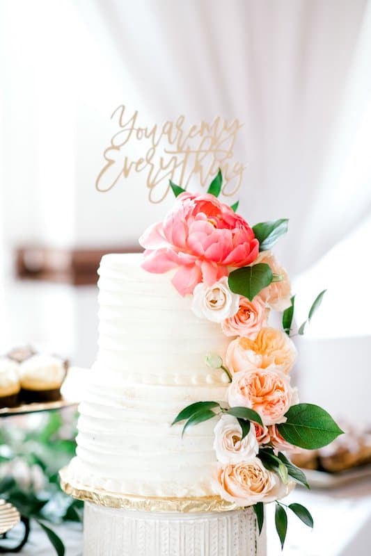 two tiered wedding cake decorated with multiple types of colorful flowers