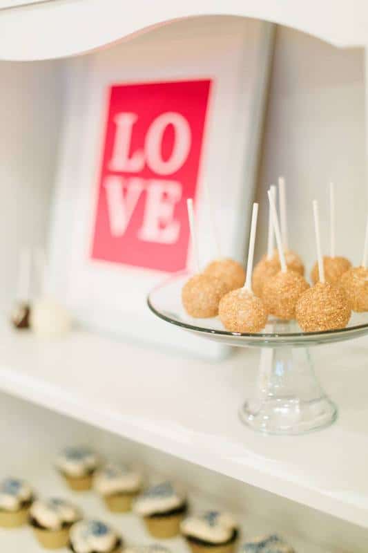 cakepops and cupcakes on display on a shelf with a Love sign next to them