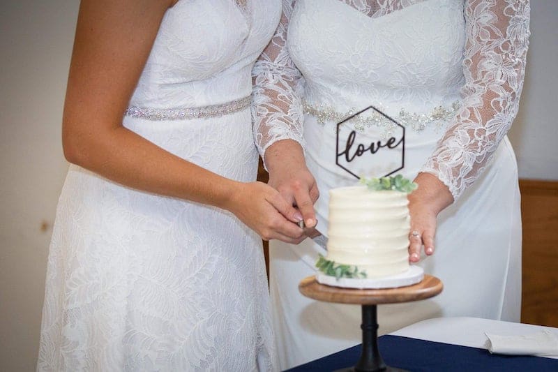 two brides cutting their wedding cake