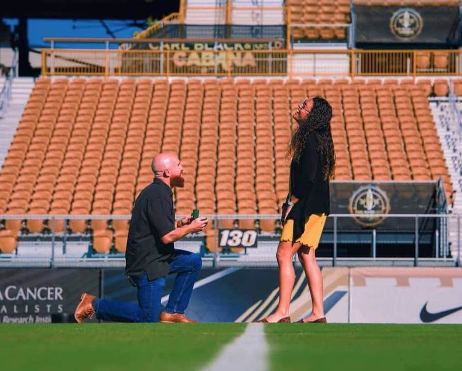 man on one knee proposing to girl in the middle of college football stadium with a UCF marriage proposal