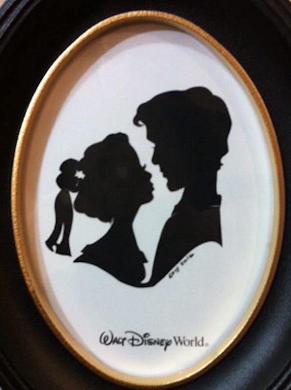 side profile of two lovers kissing in an oval frame