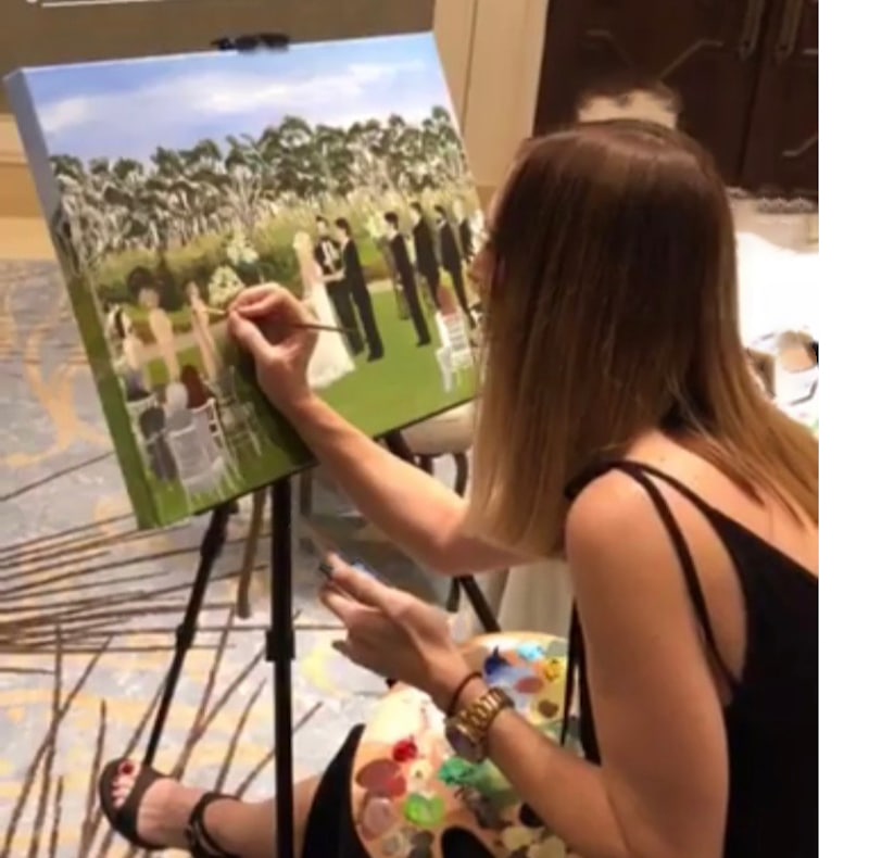woman from Artistic Talent Group painting a scene of a wedding ceremony