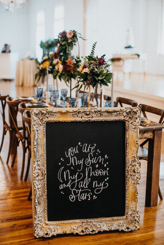 wooden table decorated for wedding ceremony with large sign that reads you are my sun my moon and all my stars by Bare Lettered Designs