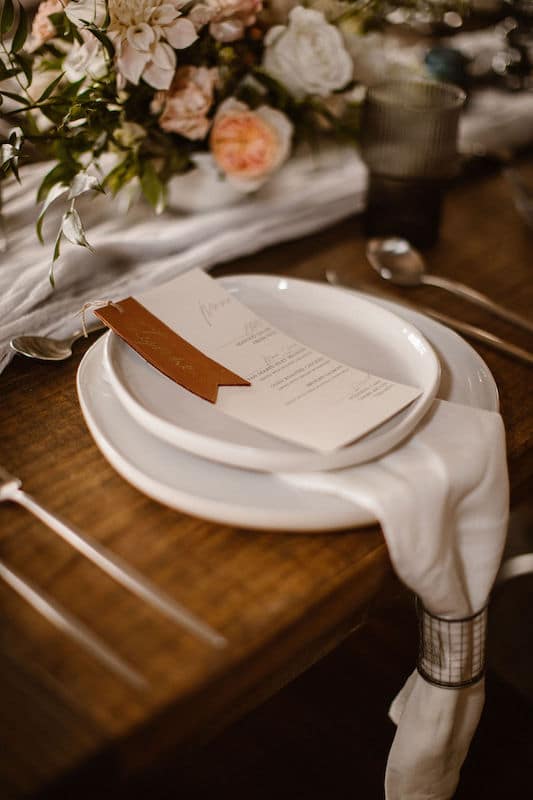 menu written and prepared by Bare Lettered Calligraphy sitting on plate at wedding reception