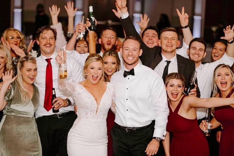 bride and groom cheering while they and their guests raise their drinks