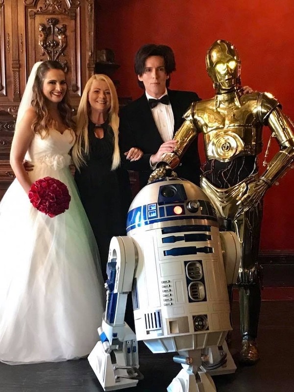 bride and groom standing next to C-3PO and R2D2