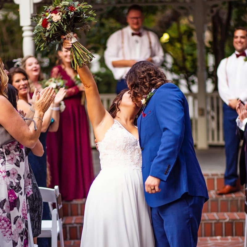 bride and groom kissing while their guests cheer