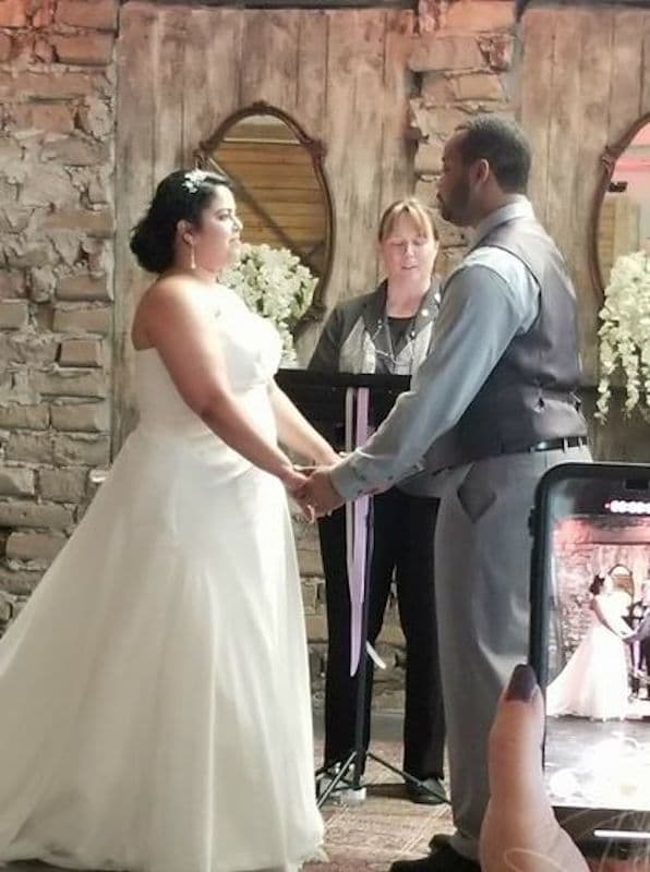 bride and groom holding hands while someone takes a picture with their cell phone during the wedding ceremony with the Humanist Celebrant Orlando