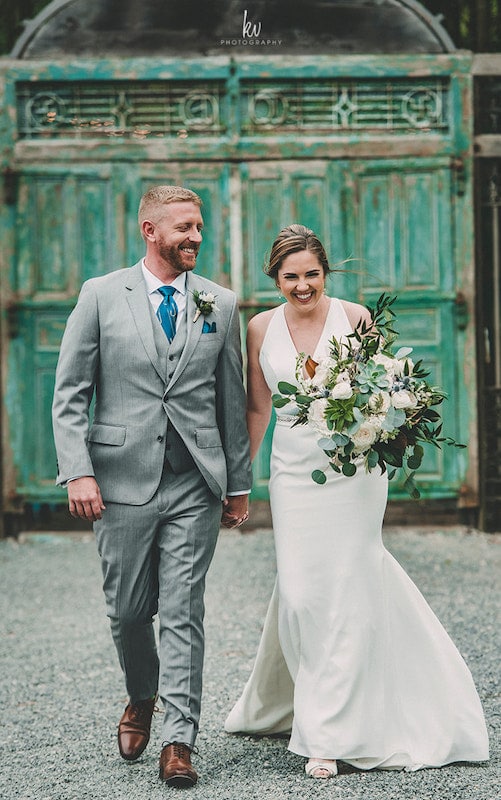 bride and groom walking on a path in front of a rustic green door