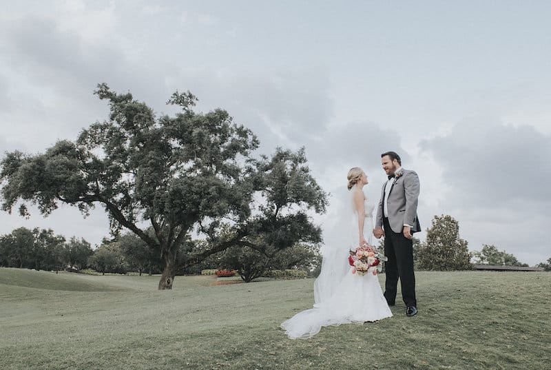 bride and groom holding hands while standing on a golf course after their wedding