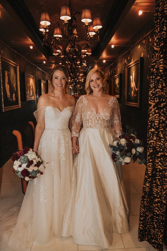 two brides holding hands and their matching flower bouquets