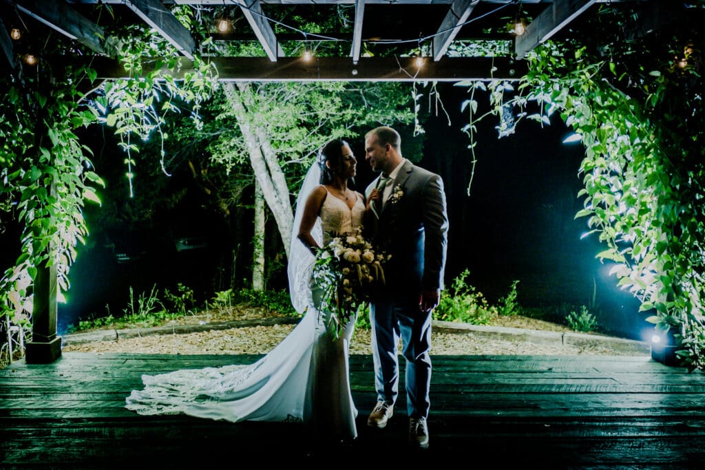 bride and groom standing under covered walkway at night at Chapel Valley Farm