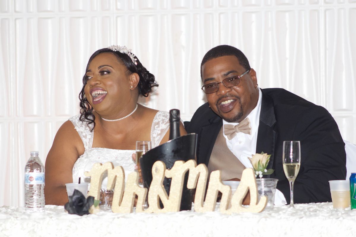 bride and groom smiling and laughing while sitting at their sweetheart table