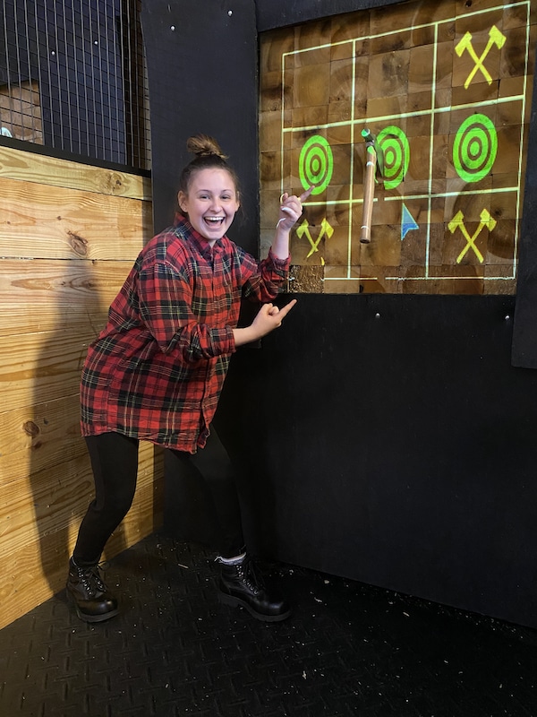 woman smiling after getting bullseye at Axecelsior Axe Throwing