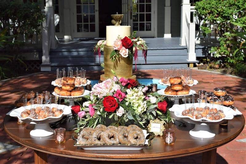 round table holding several different types of donuts, donut holes, and a wedding cake from Florida Candy Buffets