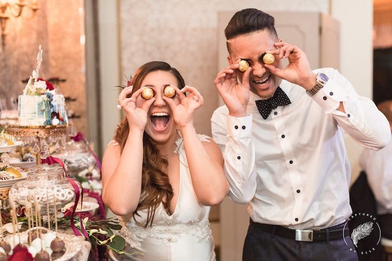 bride and groom smiling as they hold cake pops up to their eyes