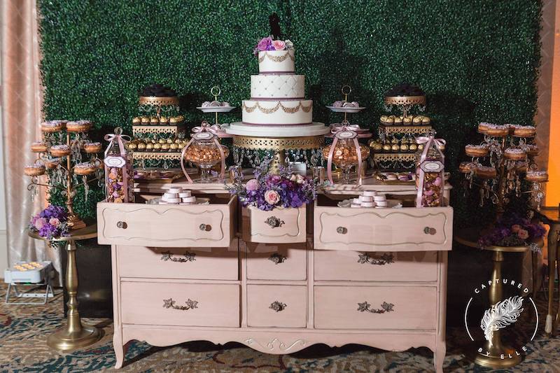 large dessert table from Florida Candy Buffets on a pink dresser in front of vine wall