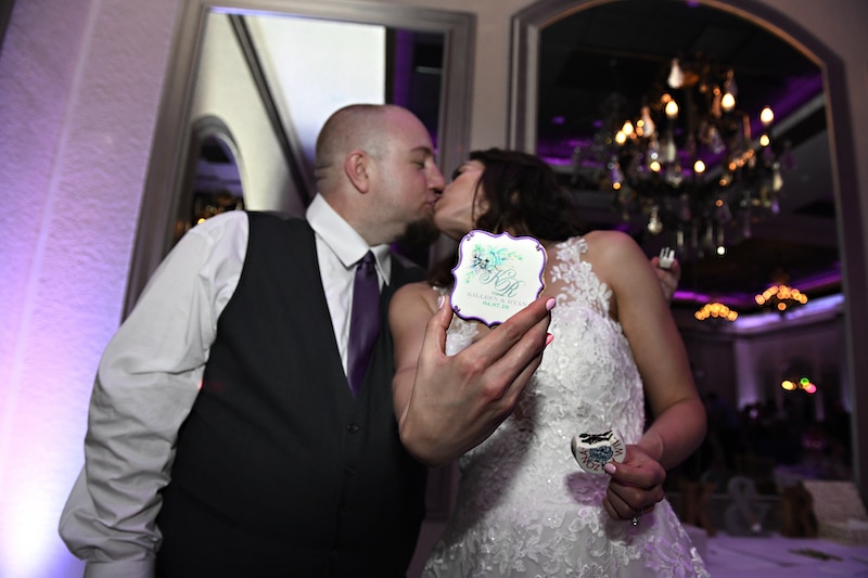 bride and groom kissing while holding custom cookie from Florida Candy Buffets