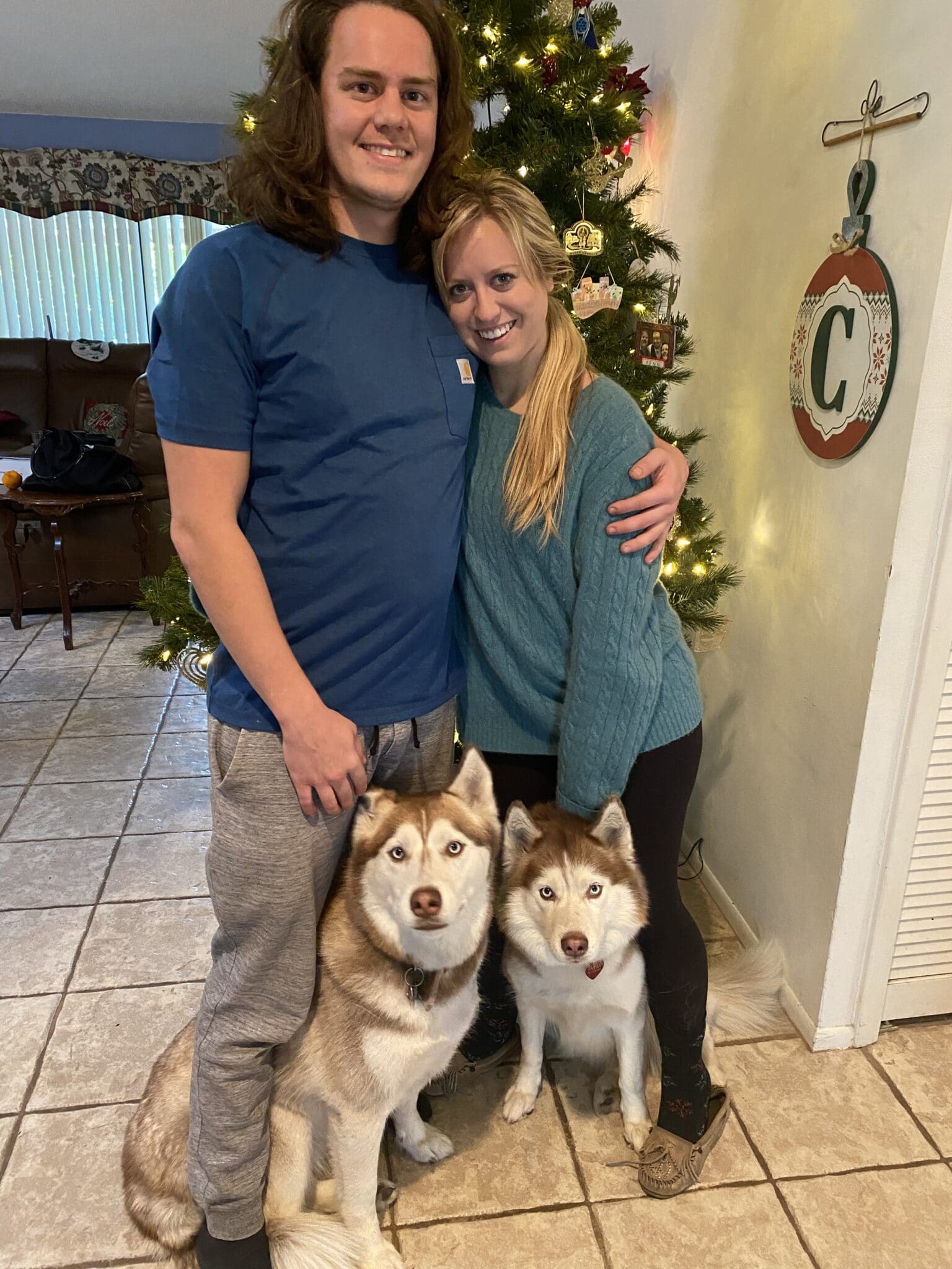 newly engaged couple standing with their two brown and white dogs between their legs