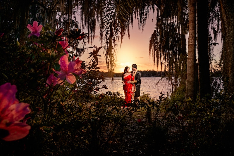 bride and groom embracing on the shores of a lake at sunset by Lazzat Photography