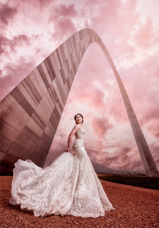 bride standing at the base of the gateway arch by Lazzat Photography