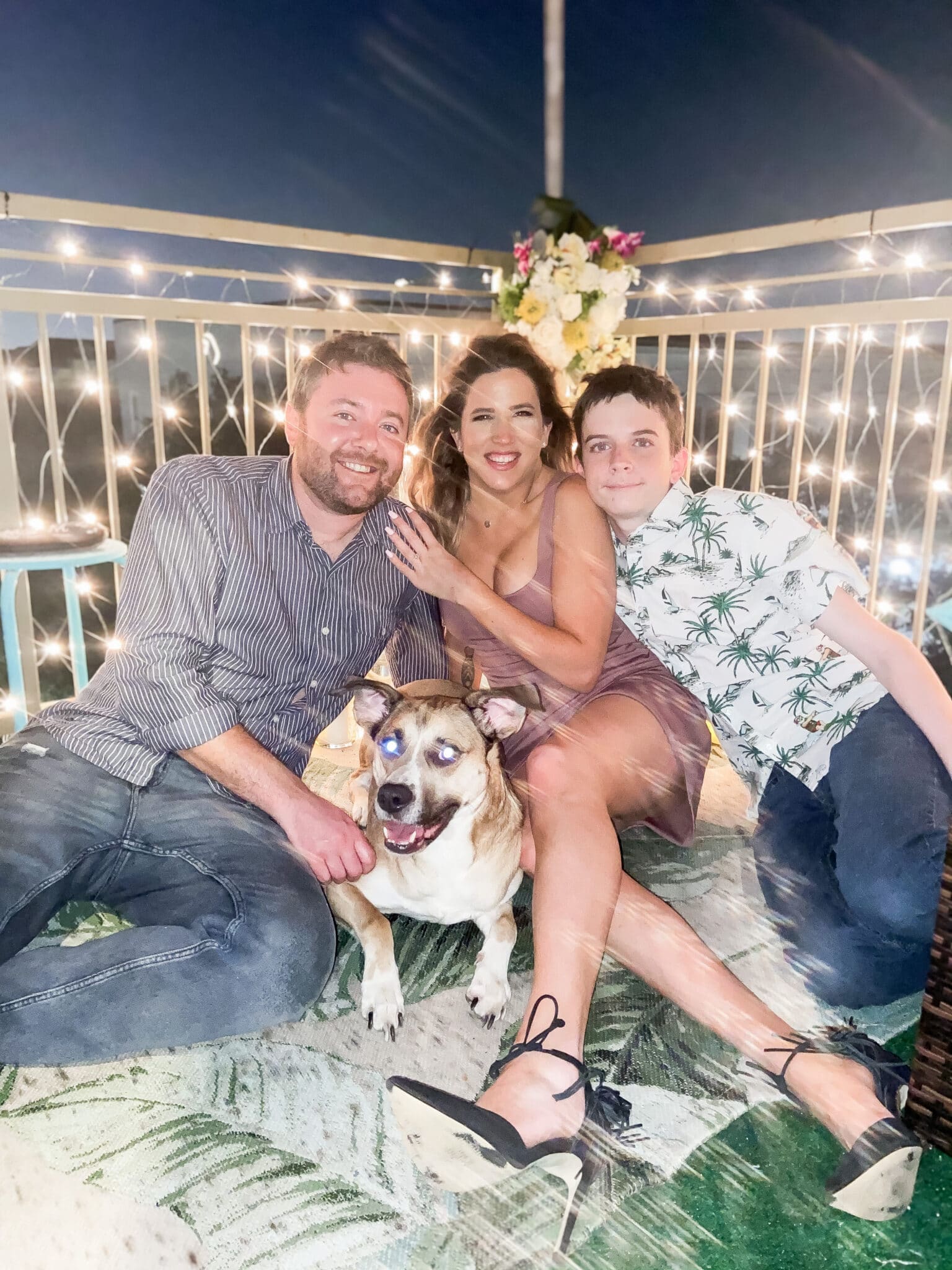 newly engaged couple on the balcony right after their engagement with their son and dog