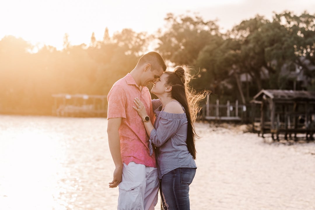 newly engaged couple standing forehead to forehead with a river in the background