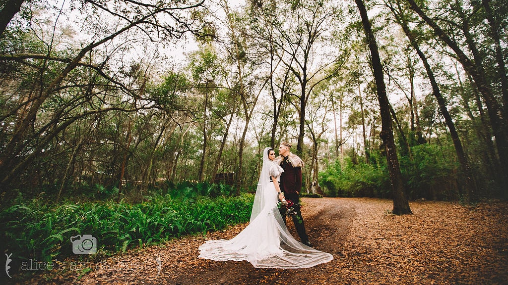 bride and groom stand together for wedding portrait outside in woods for viking themed wedding day