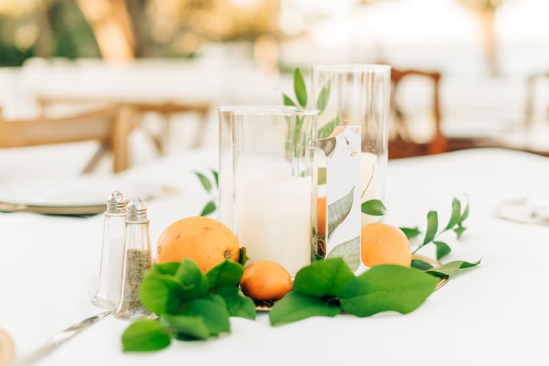wedding table centerpieces with candles, oranges, and green leaves