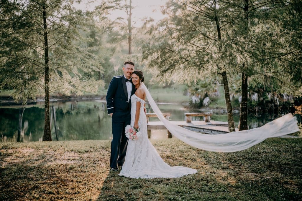 bride and groom standing next to pond at Cypress Creek Farmhouse