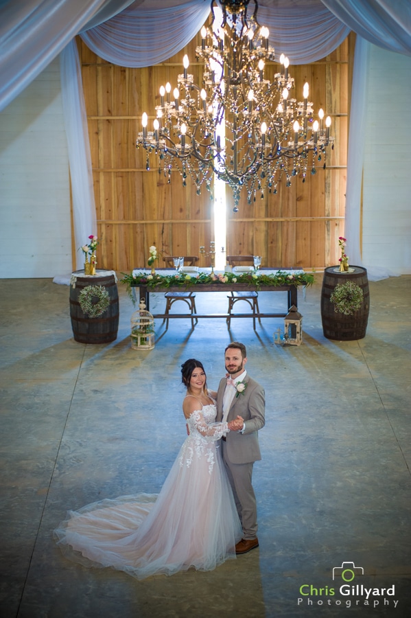 bride and groom dancing inside in front of barn doors