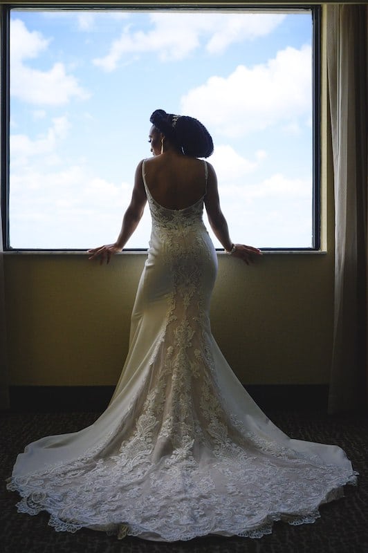 bride standing in wedding dress looking out the window, photo taken by Nativ Lens