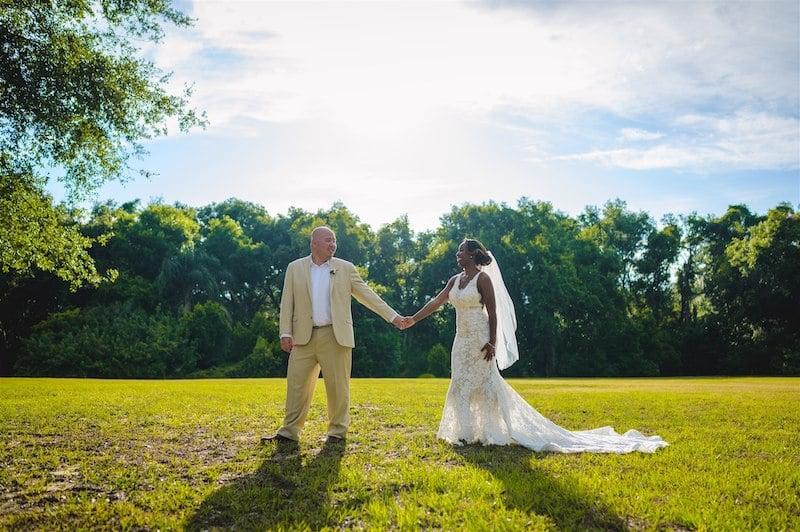 bride and groom holding hands outside in a large field, photo taken by Nativ Lens