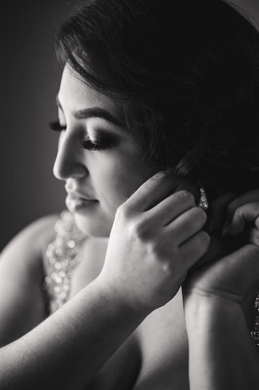 bride putting her earrings in while preparing for her wedding, photo taken by Nativ Lens