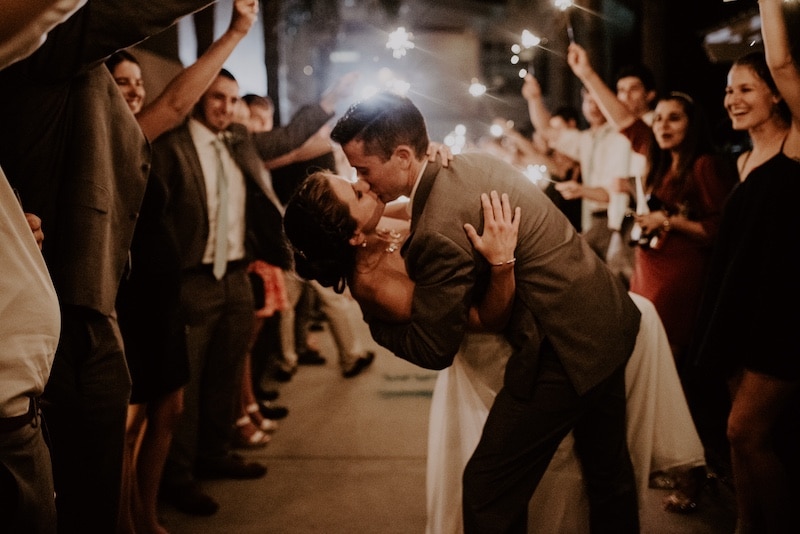 groom dipping bride and kissing her at end of sparkler exit