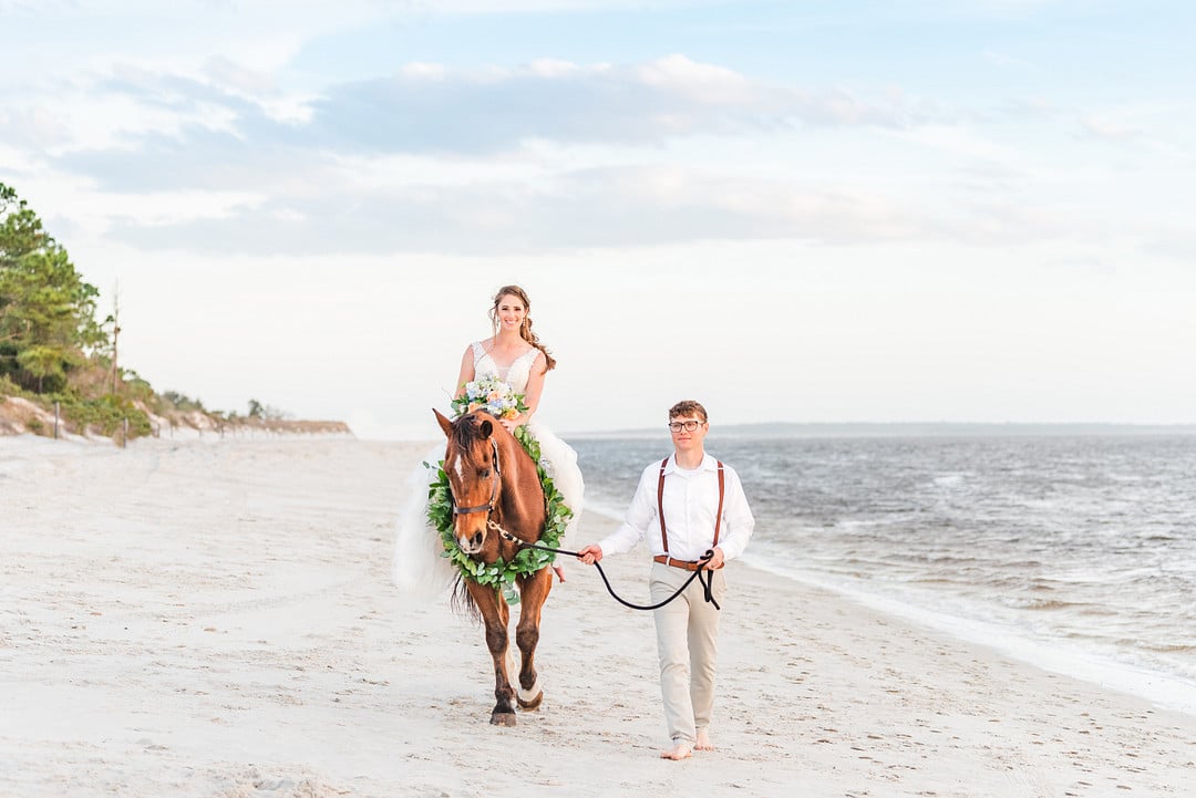 bride on a horse walking next to groom on amelia island