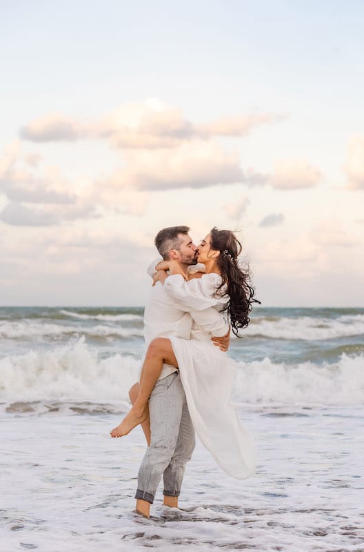 man and woman kissing while standing in the waves of the ocean after getting engaged, SMO Photography