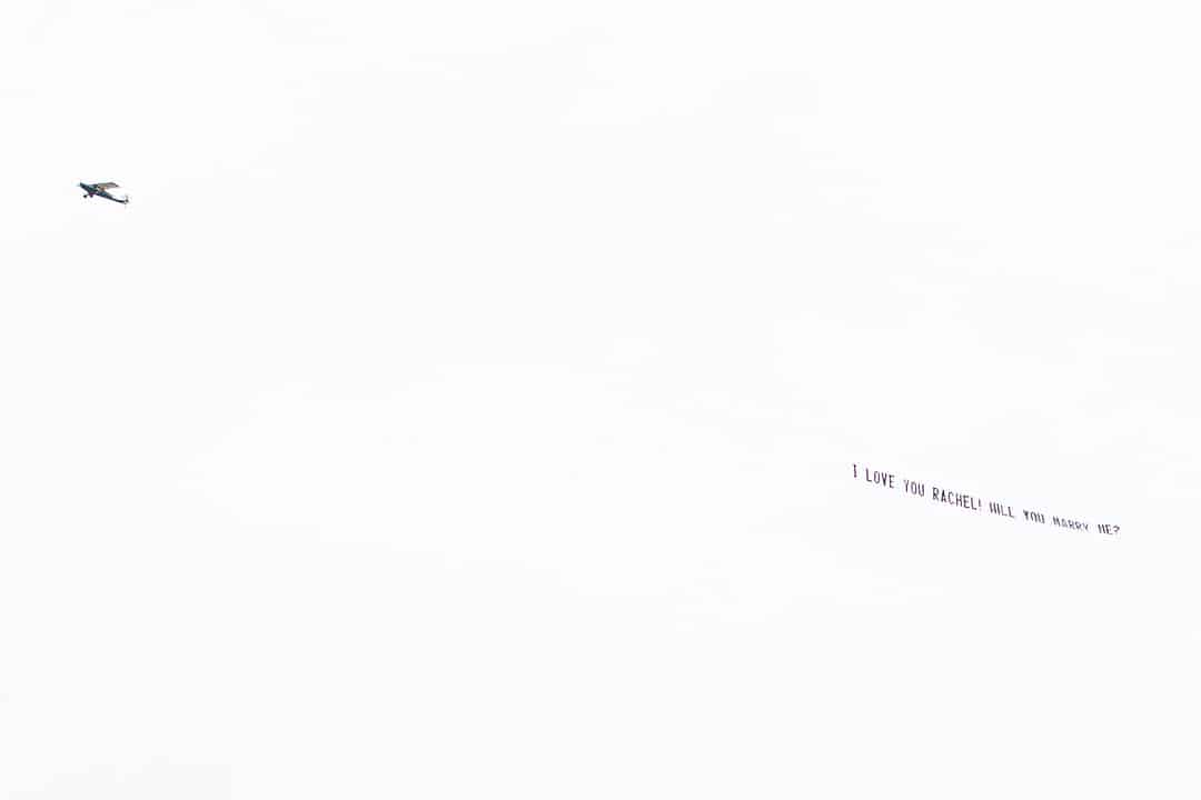 plane flying a banner asking the bride to be to marry the groom to be