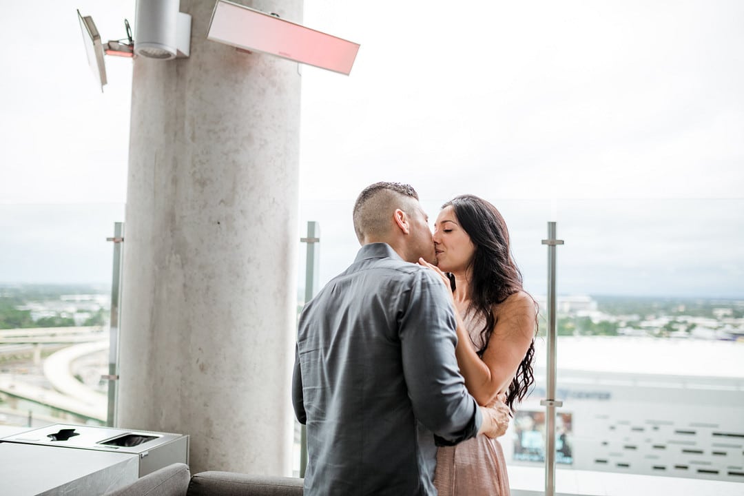 bride and groom to be kissing on the rooftop bar