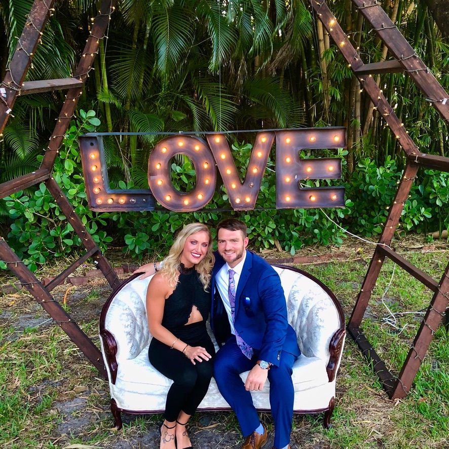 bride and groom to be sitting under a sign that says love smiling